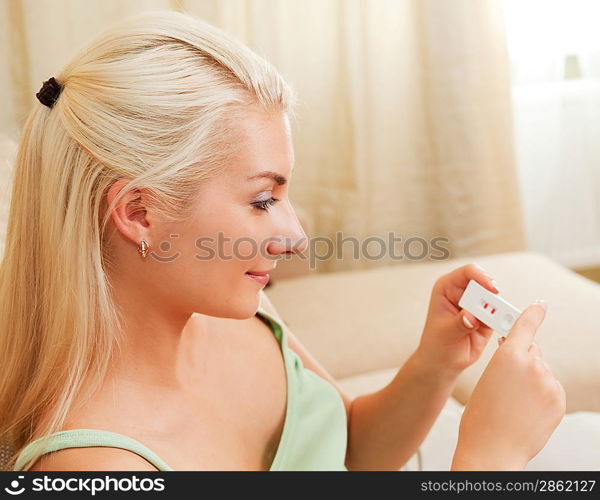 Happy young woman holding positive pregnancy test
