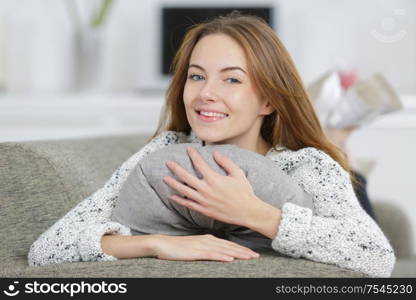 happy young woman hugging a gray pillow
