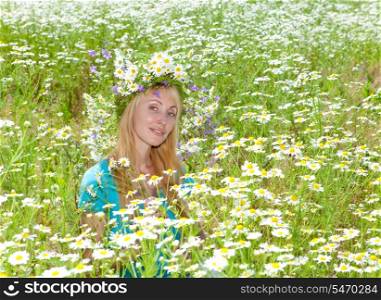 happy young woman in a wreath from wild flowers in the chamomile field