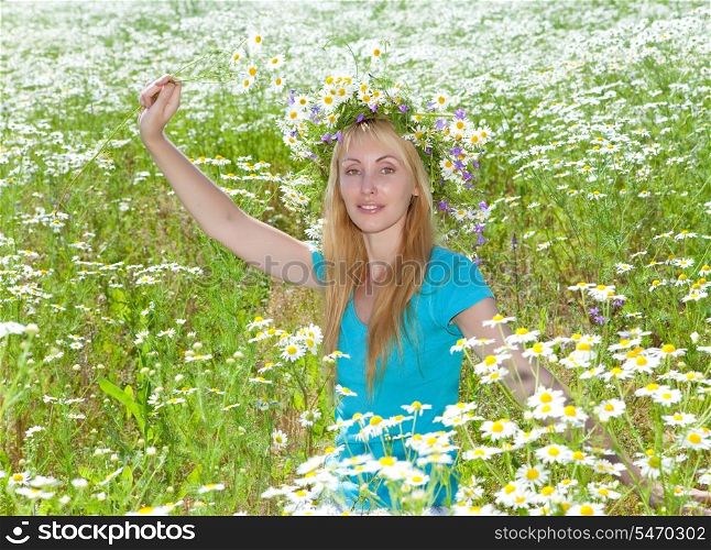 happy young woman in a wreath from wild flowers in the chamomile field