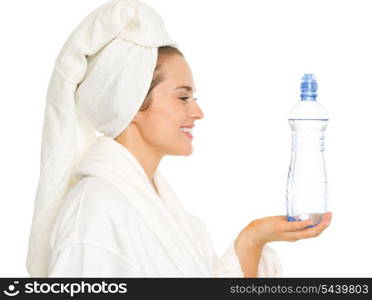 Happy young woman in bathrobe holding bottle with water