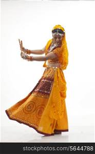 Happy young woman in chaniya choli performing Dandiya Raas against white background