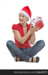 Happy young woman in Christmas hat sitting on floor with present box