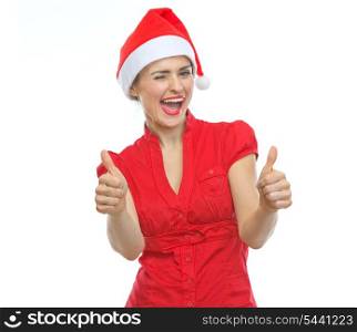 Happy young woman in Christmas hat winking and showing thumbs up