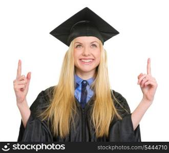 Happy young woman in graduation gown pointing up on copy space