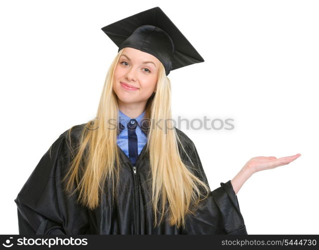 Happy young woman in graduation gown presenting something on empty palm