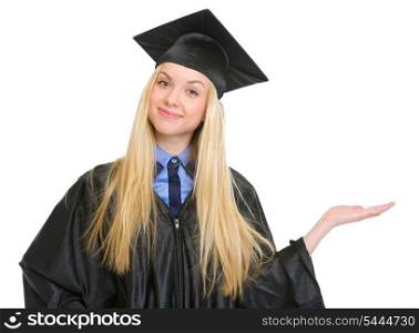 Happy young woman in graduation gown presenting something on empty palm