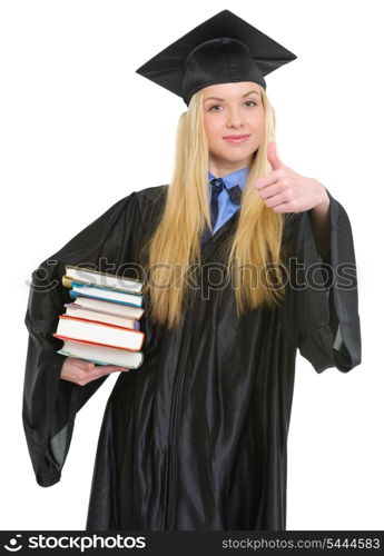 Happy young woman in graduation gown showing books and thumbs up