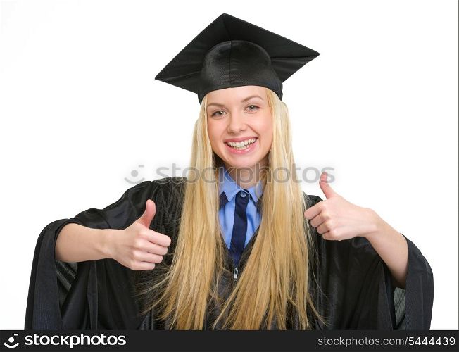 Happy young woman in graduation gown showing thumbs up