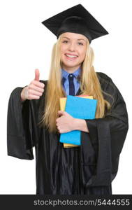 Happy young woman in graduation gown with books showing thumbs up