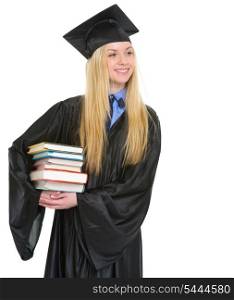 Happy young woman in graduation gown with stack of books looking on copy space