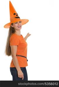 Happy young woman in Halloween hat pointing on back