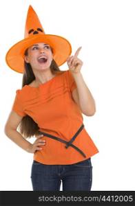 Happy young woman in Halloween hat pointing on copy space