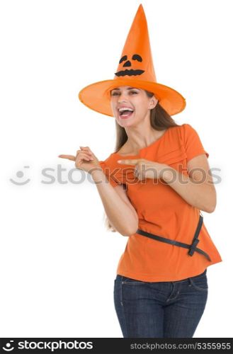 Happy young woman in Halloween hat pointing side