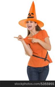 Happy young woman in Halloween hat pointing side