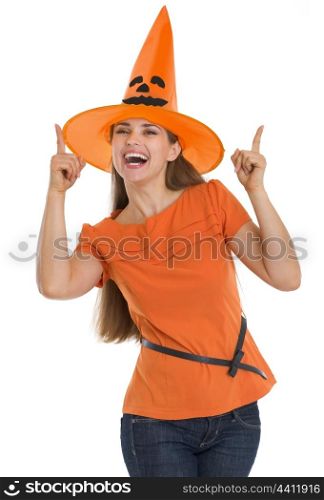 Happy young woman in Halloween hat pointing up