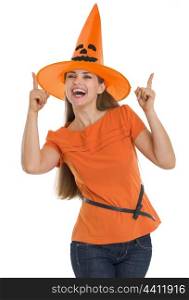 Happy young woman in Halloween hat pointing up