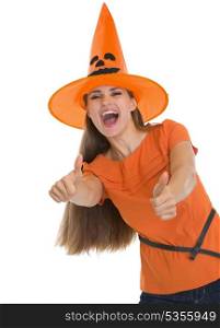 Happy young woman in Halloween hat showing thumbs up
