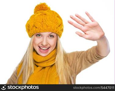 Happy young woman in hat and scarf greeting