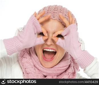 Happy young woman in knit winter clothes looking through glasses shaped hands