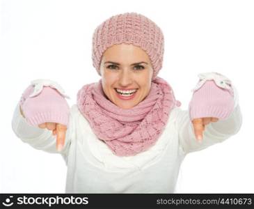 Happy young woman in knit winter clothing pointing down