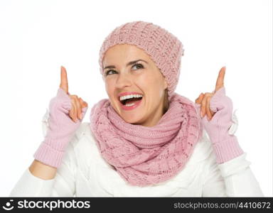 Happy young woman in knit winter clothing pointing up