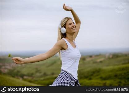 Happy young woman in∑mer nature listening toμsic on headpho≠s