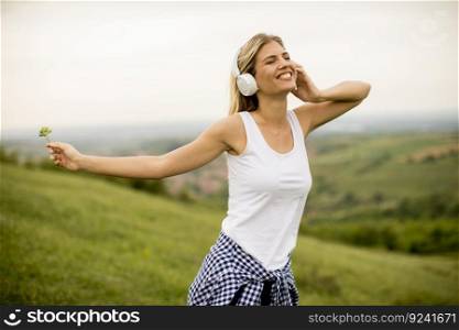 Happy young woman in nature listening to music on headphones