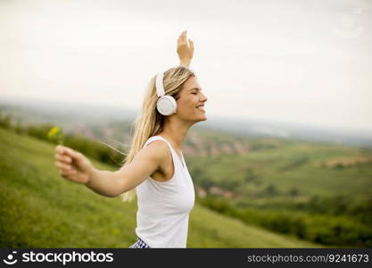 Happy young woman in nature listening to music on headphones