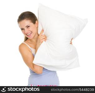 Happy young woman in pajamas looking out from pillow