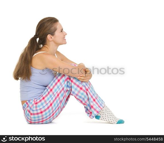 Happy young woman in pajamas sitting and looking on copy space