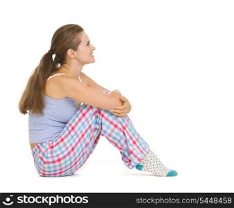 Happy young woman in pajamas sitting and looking on copy space