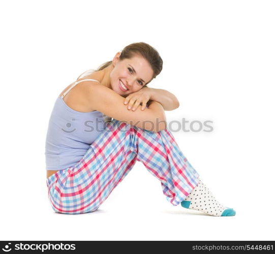 Happy young woman in pajamas sitting on floor isolated on white