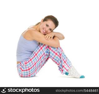 Happy young woman in pajamas sitting on floor isolated on white