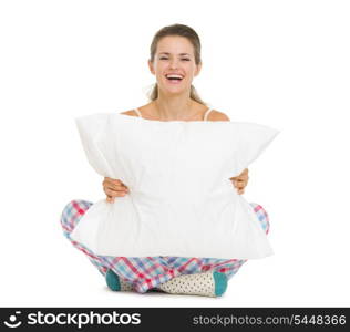 Happy young woman in pajamas sitting with pillow