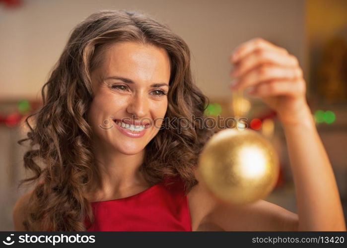 Happy young woman in red dress holding christmas ball