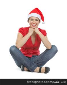 Happy young woman in Santa hat sitting on floor