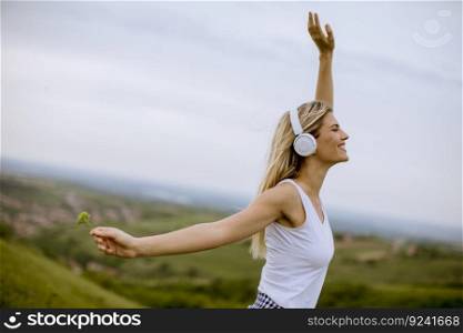 Happy young woman in summer nature listening to music on headphones