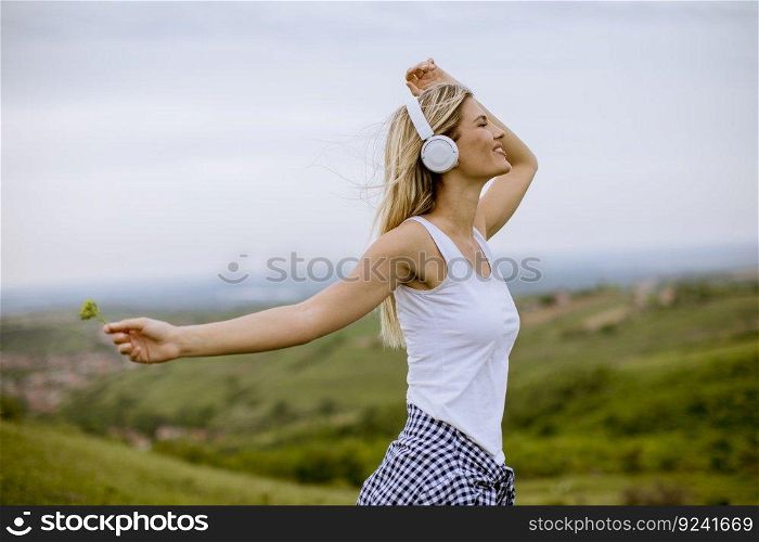 Happy young woman in summer nature listening to music on headphones