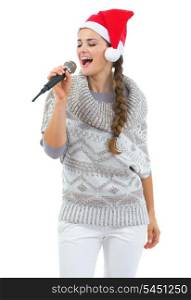 Happy young woman in sweater and christmas hat singing in microphone