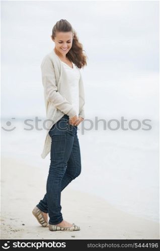 Happy young woman in sweater enjoying lonely beach