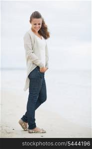 Happy young woman in sweater enjoying lonely beach