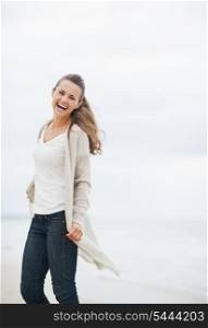 Happy young woman in sweater having fun time on lonely beach