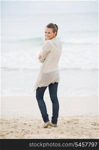 Happy young woman in sweater on beach