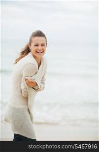 Happy young woman in sweater on coldly beach