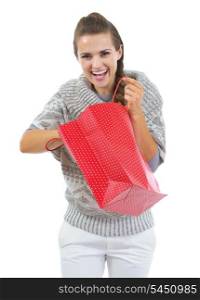 Happy young woman in sweater pulling out something from red christmas shopping bag