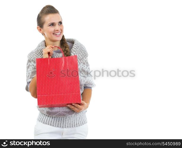 Happy young woman in sweater with red christmas shopping bag looking on copy space