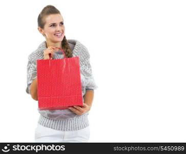 Happy young woman in sweater with red christmas shopping bag looking on copy space