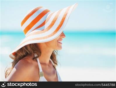 Happy young woman in swimsuit and beach hat looking on copy space
