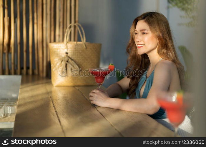 happy young woman in swimsuit enjoying with a fresh cocktail at bamboo wooden bar